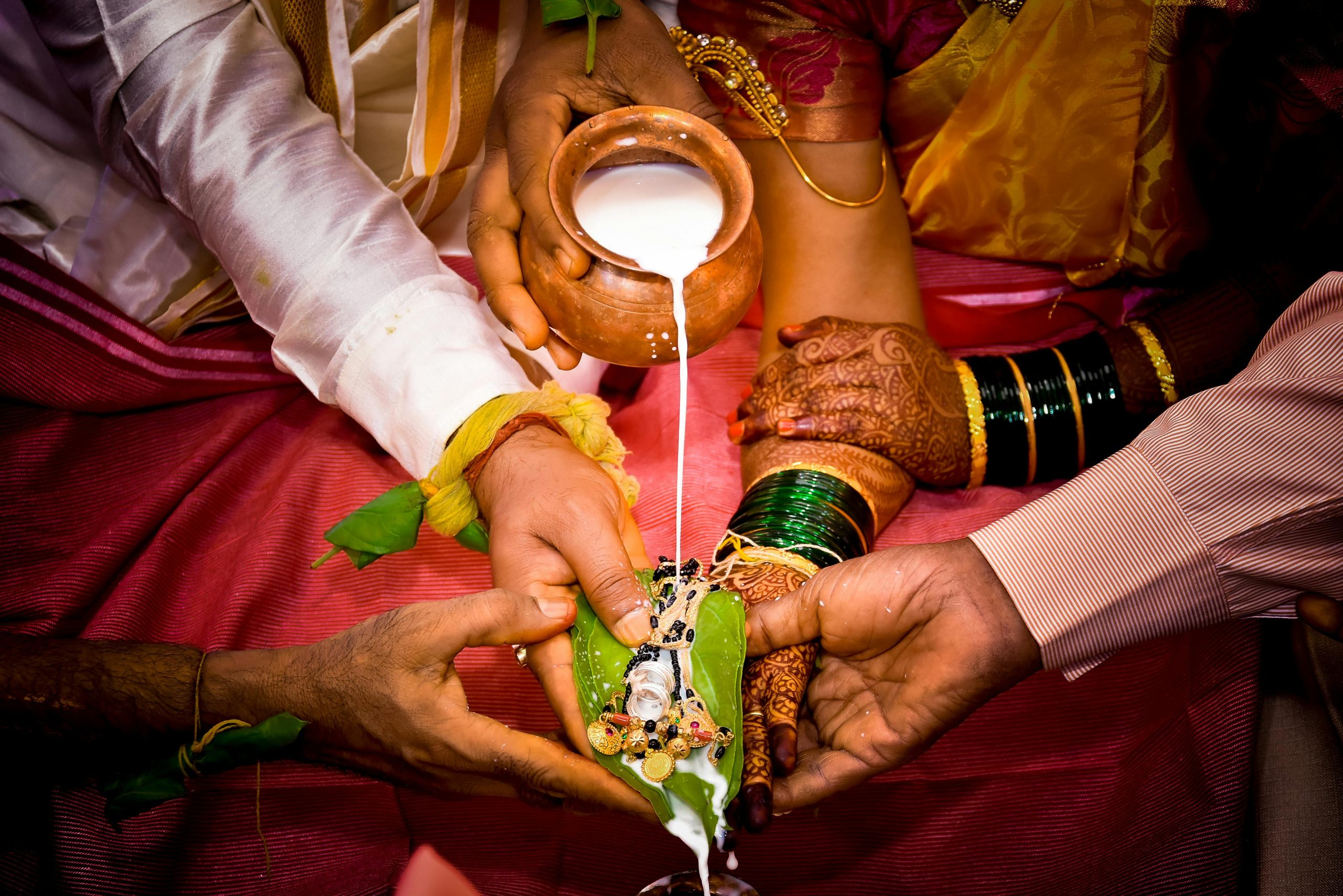 Close-up of a traditional Indian wedding ritual involving milk pouring on hands, depicting cultural values and symbolism.